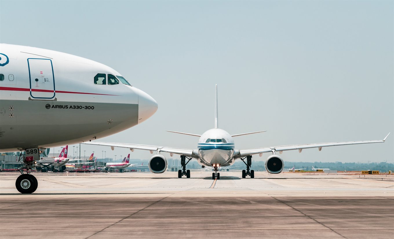 空港の駐機場に並ぶ旅客機と、出発を待つ滑走路の光景